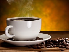 Cup of coffee with coffee beans on a beautiful brown background.